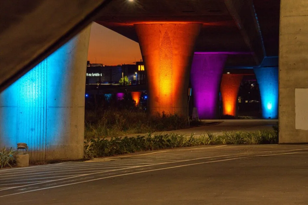 Bridge columns washed in colored light at the river park by Snapdragon Stadium