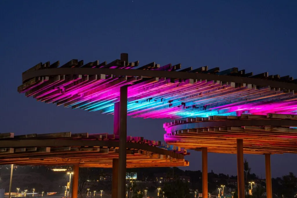 Shade canopies lit in pink and blue at the river park by Snapdragon Stadium