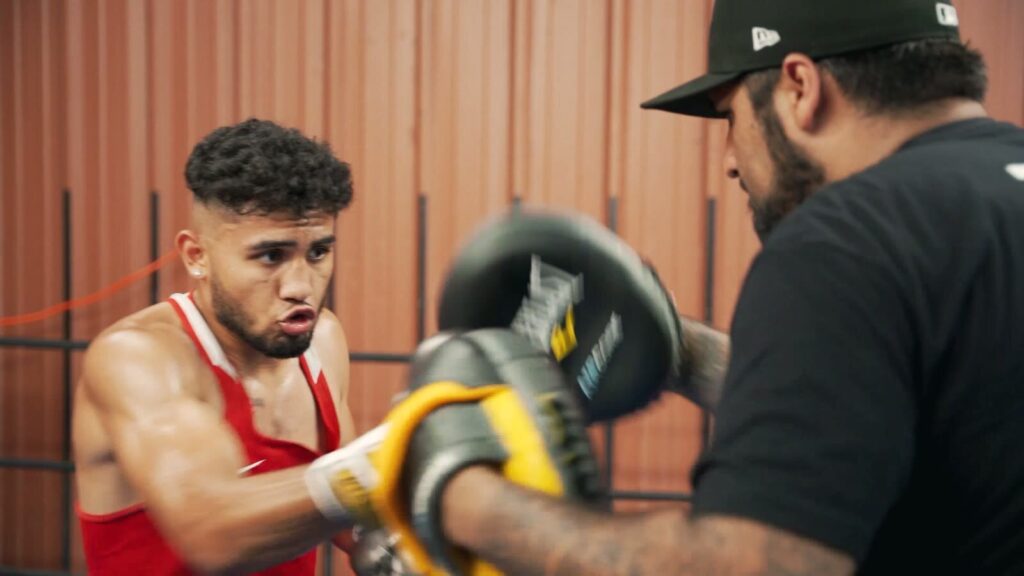 Jorge in red gloves with his coach in a Spring Valley boxing gym