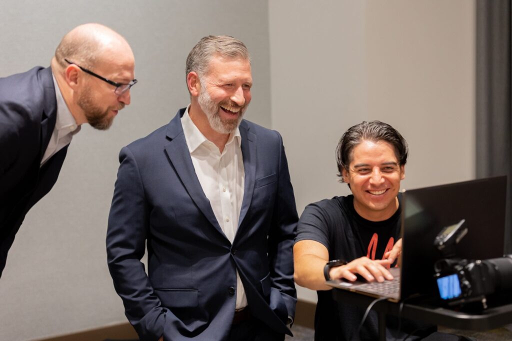 Two clients laughing as they see their headshots come up on the screen next to Eddie