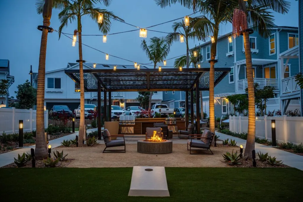 Community courtyard in Carlsbad with string lights and a fire pit at dusk