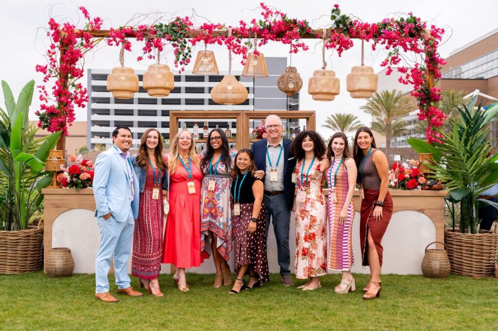 The Marzul team lined up in front of a flower-covered entrance at the grand opening