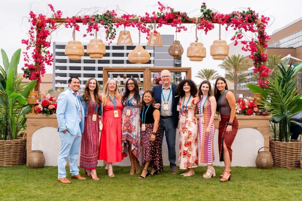 The Marzul team lined up in front of a flower-covered entrance at the grand opening