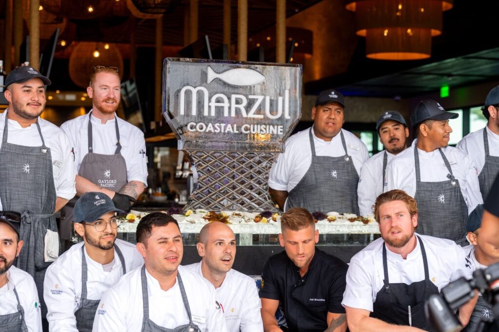 The Marzul kitchen crew in chef whites gathered under the restaurant sign