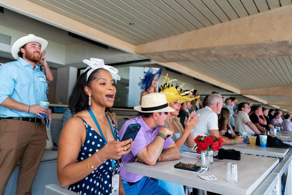 Guests laughing in the grandstand suite at the Surf and Turf event at the Del Mar Fairgrounds