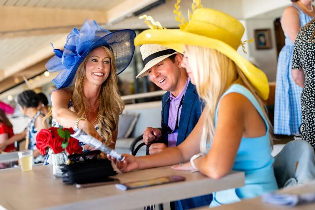 Guests in big derby hats sharing a table at the racetrack event