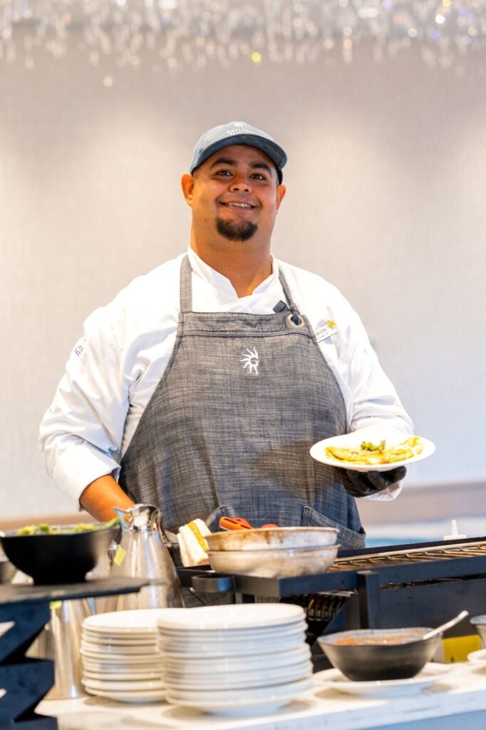 A chef plating food at a live cooking station at the racetrack event