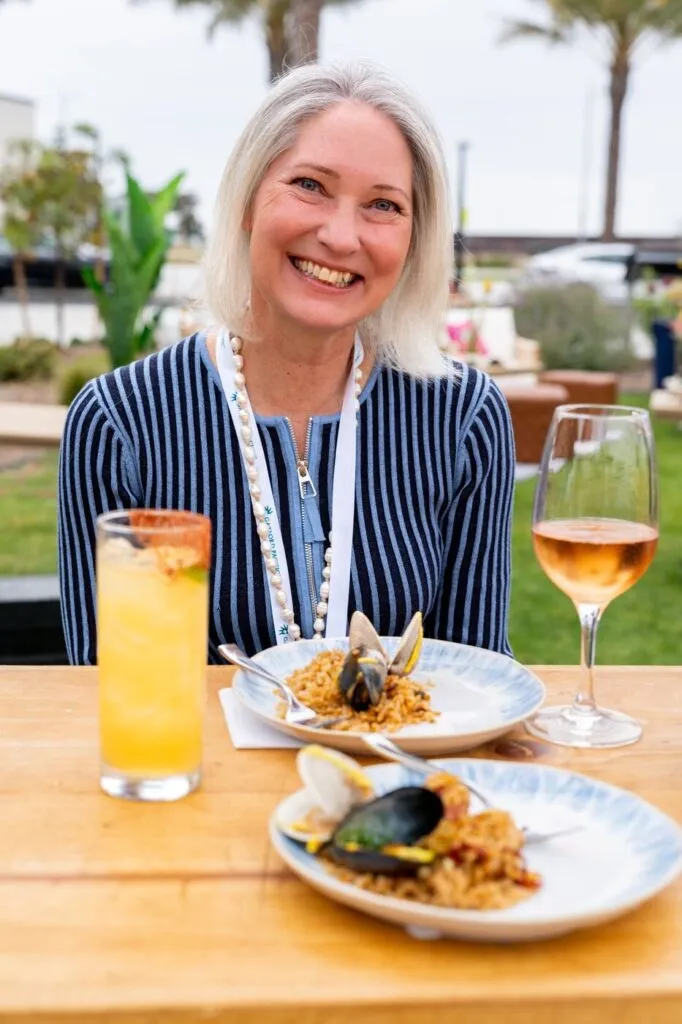 A guest smiling over paella and a glass of rose at the Marzul grand opening