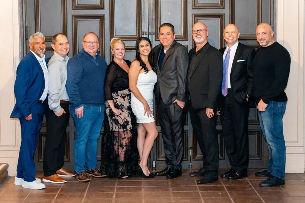 A company team lined up for a group photo at their holiday party at the Prado