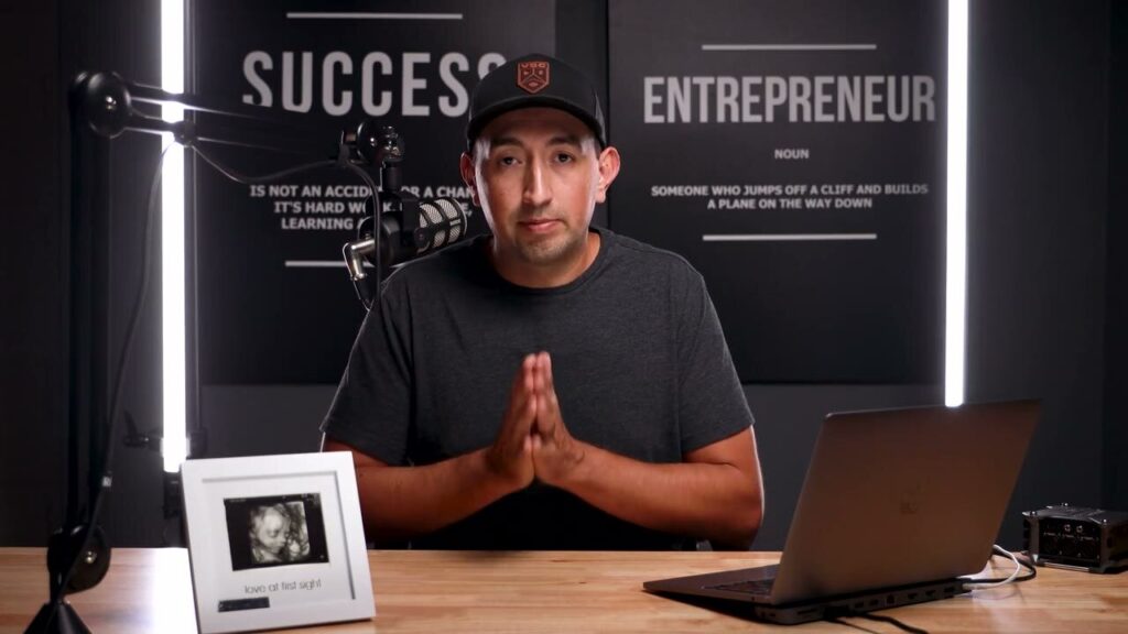 David at his desk in front of an Entrepreneur sign, recording his video review