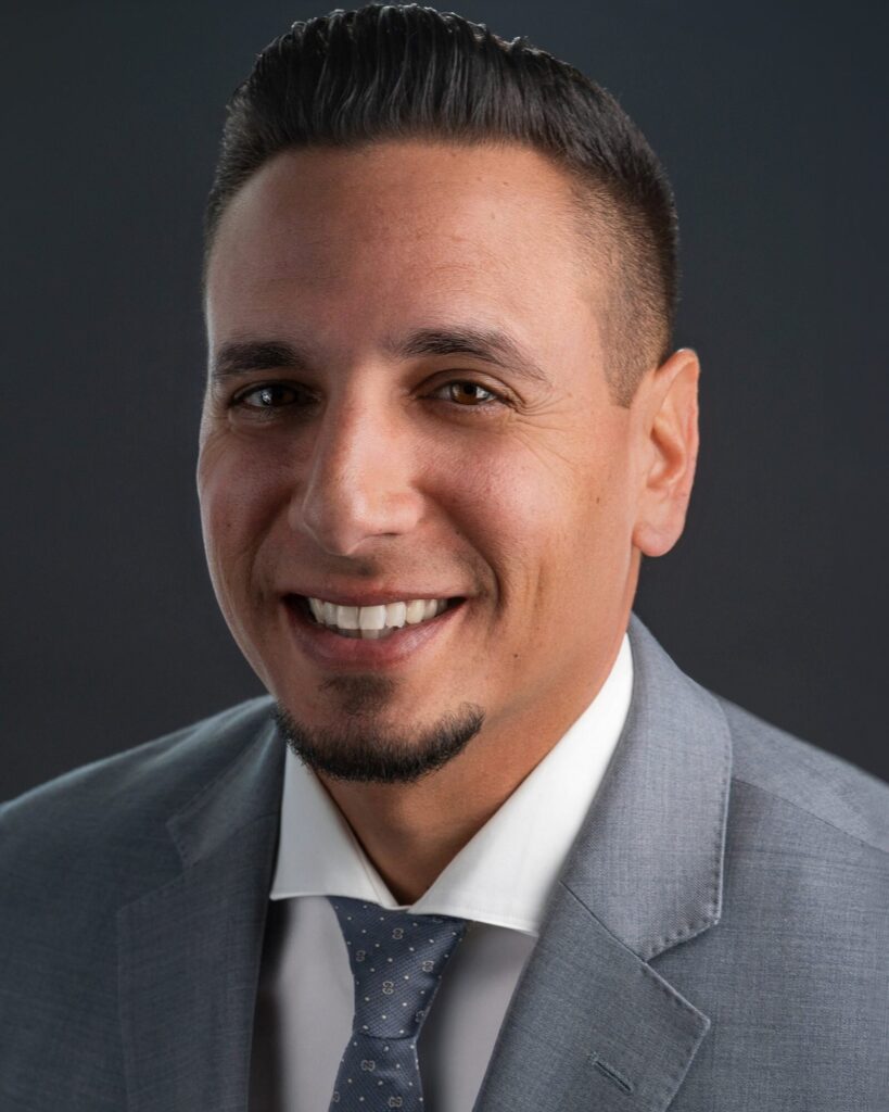 Executive headshot of a smiling man in a gray suit and tie