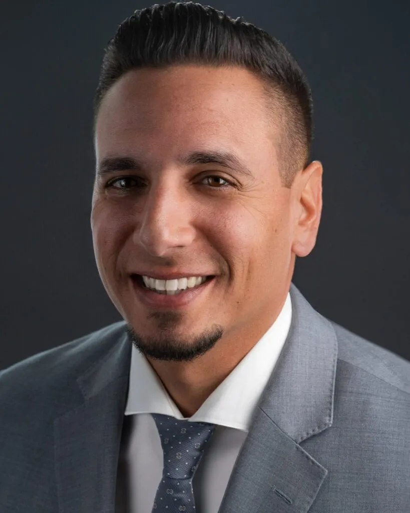 Executive headshot of a smiling man in a gray suit and tie