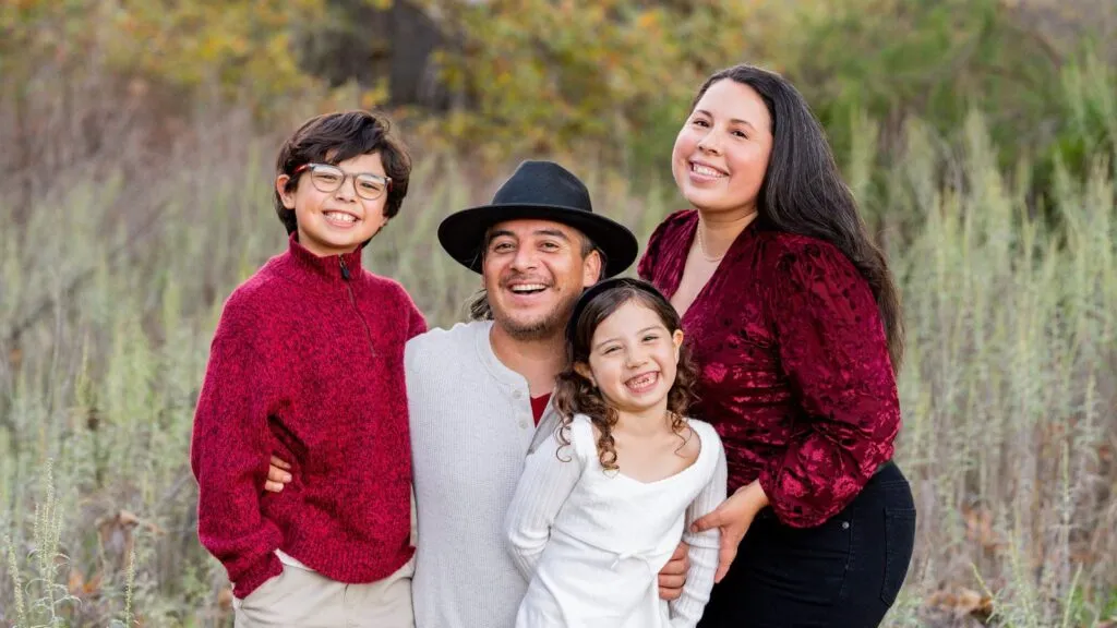 Eddie Flores laughing with his wife and two kids on a fall family shoot at Steele Canyon