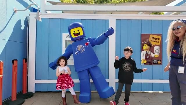 Two kids waving next to a LEGO spaceman at Legoland, from a family montage