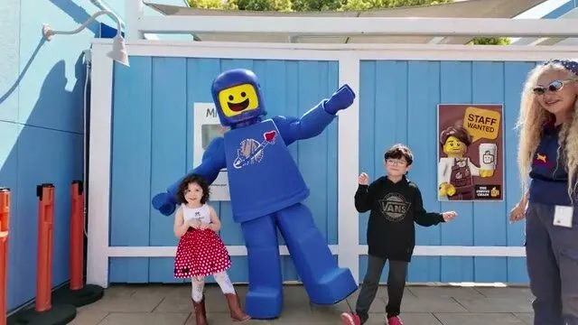 Two kids waving next to a LEGO spaceman at Legoland, from a family montage