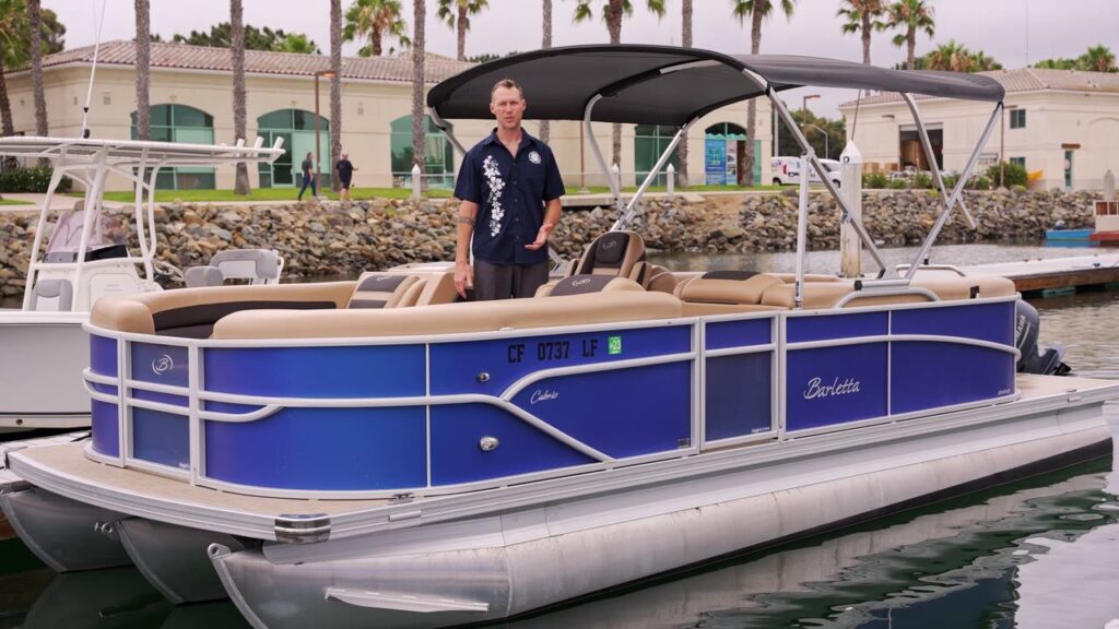 A Freedom Boat Club guide standing on a blue pontoon boat at the dock on Harbor Island
