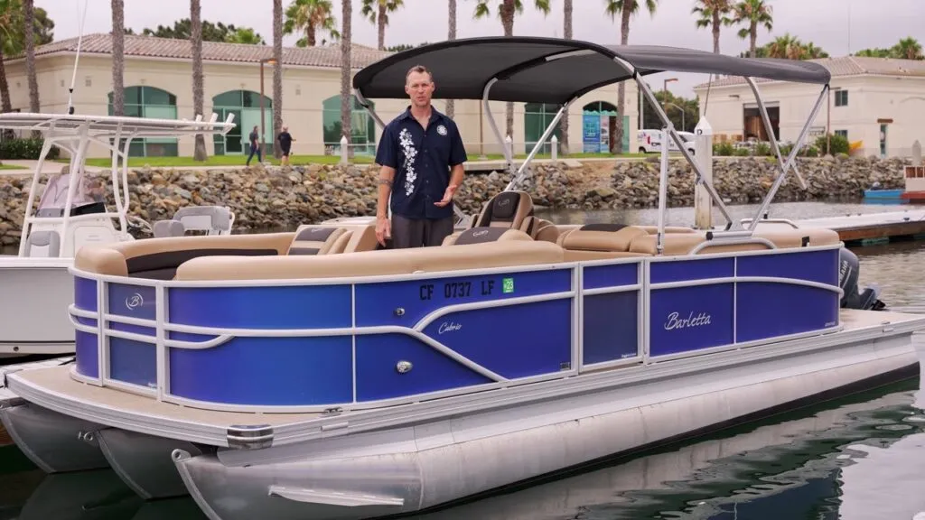 A Freedom Boat Club guide standing on a blue pontoon boat at the dock on Harbor Island
