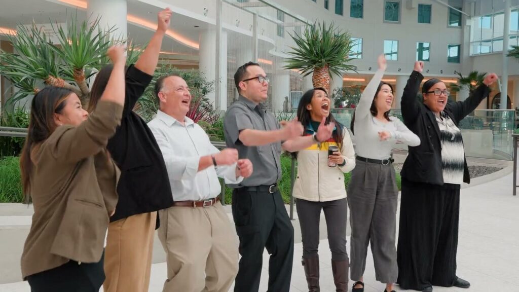 Gaylord Pacific team members cheering with their arms up in the resort lobby