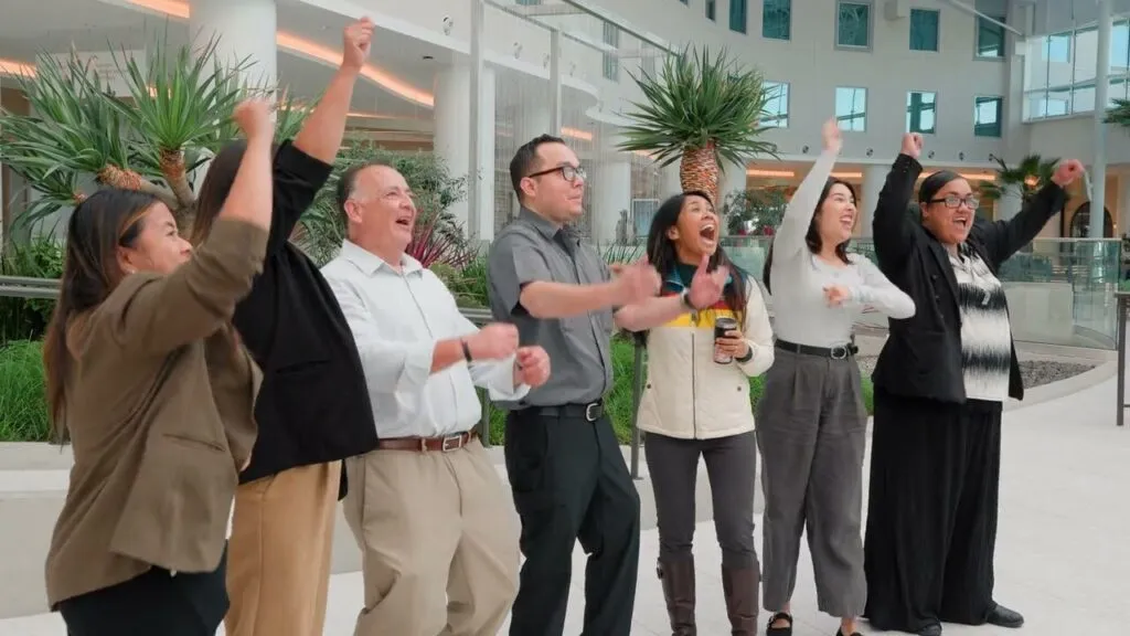 Gaylord Pacific team members cheering with their arms up in the resort lobby