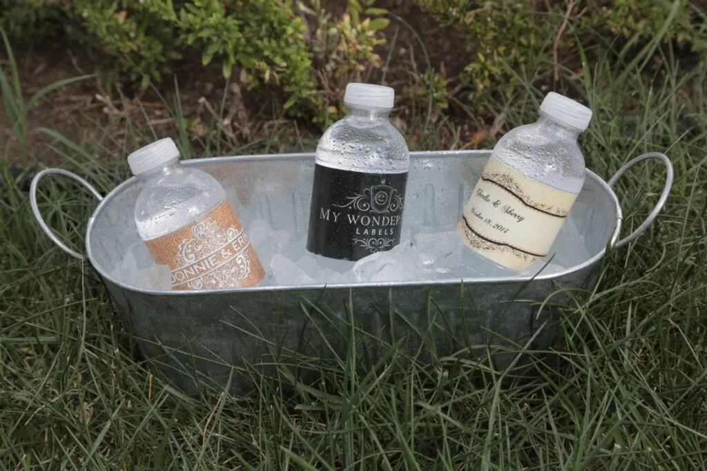 Custom labeled water bottles in an ice bucket on the grass