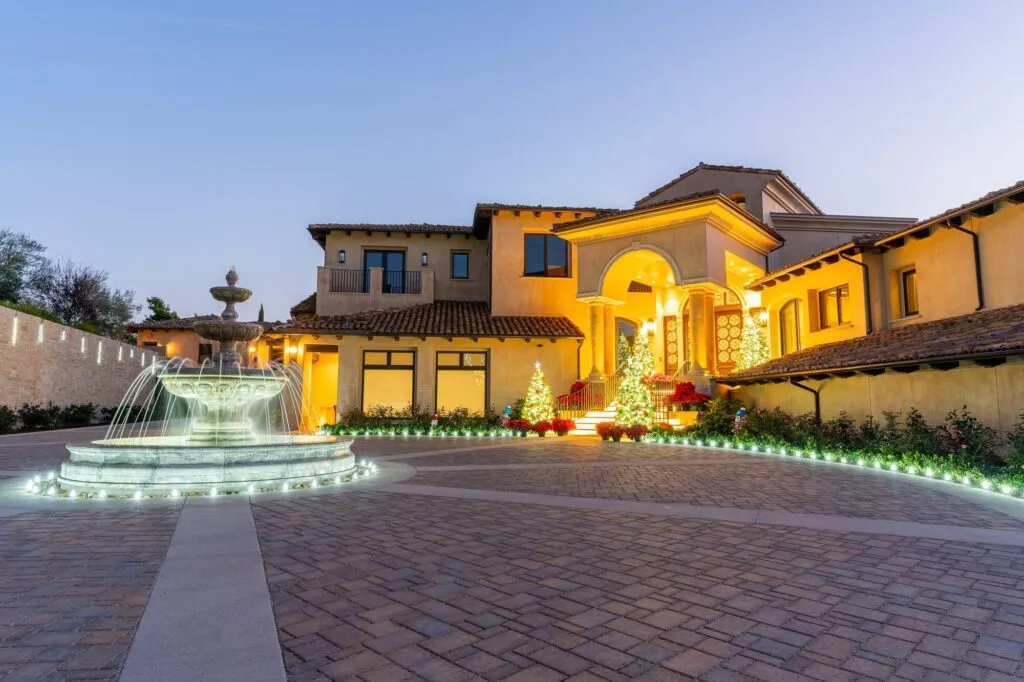 Estate in Rancho Santa Fe at dusk with a lit fountain in the motor court