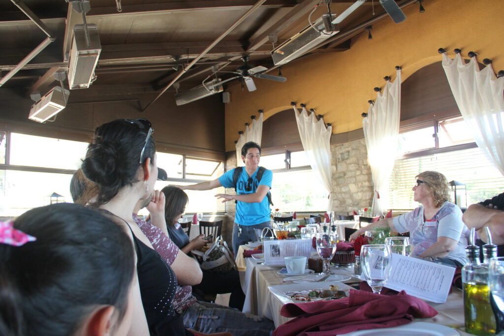 Eddie Flores standing at the head of a long table, talking to a seated group at the first Chula Vista Photography Meetup in 2013