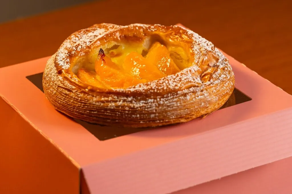 Apricot danish sitting on its pink bakery box