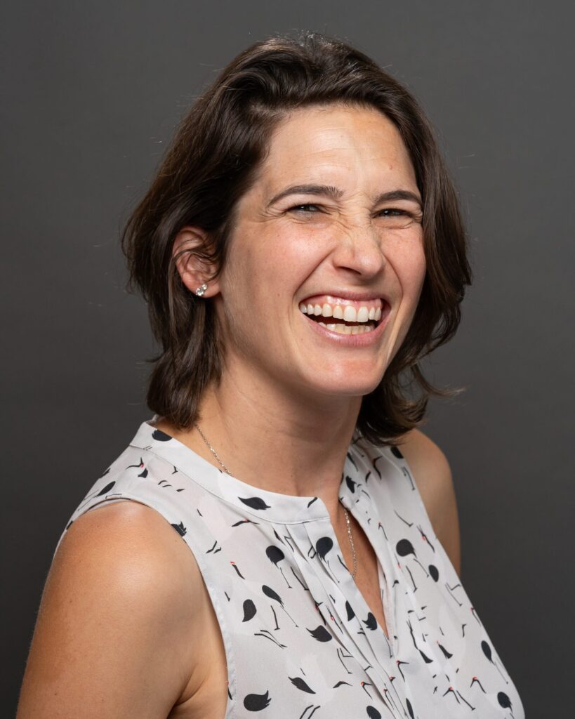 Corporate headshot of a woman caught mid-laugh on a charcoal backdrop