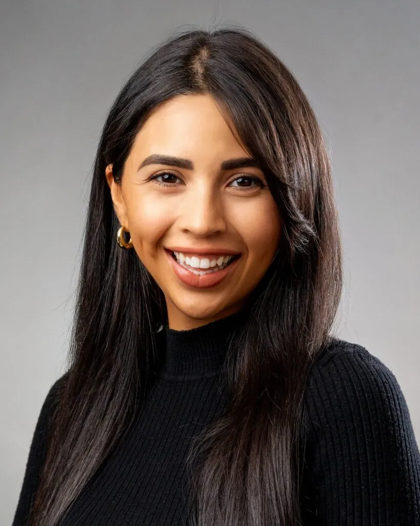 Headshot of a smiling woman in a black sweater on a light gray background