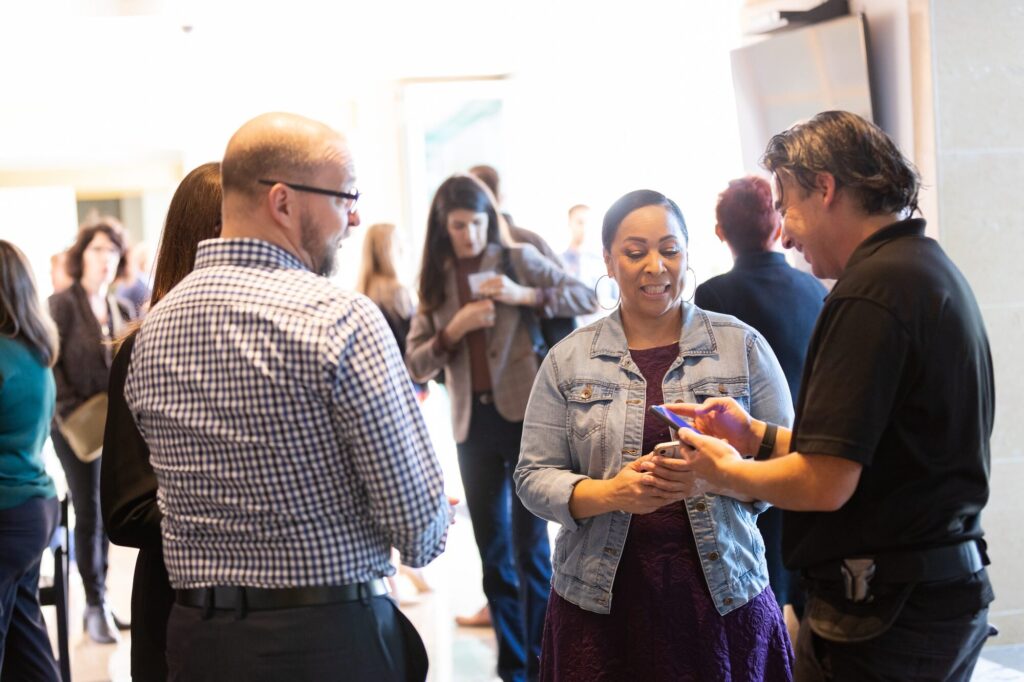 Eddie Flores walking a business owner through something on her phone in a room full of people