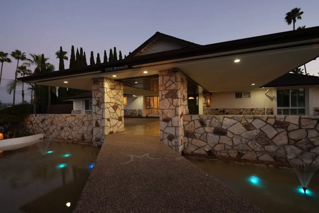 Stone entry of a home at twilight with lit pathway lights